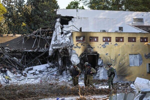 Israeli soldiers walk past houses destroyed by Hamas militants in Kibbutz Be'eri, Israel, Saturday, Oct. 14, 2023. (AP Photo/Ariel Schalit)