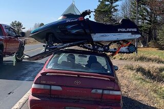 This undated photo provided by The Wisconsin Department of Transportation shows a snowmobile strapped to the roof of a Toyota Corolla in Northwestern Wisconsin Sunday Nov. 1, 2020. The Wisconsin State Patrol pulled over the driver on Highway 63 in northwestern Wisconsin Sunday afternoon after seeing the snowmobile perched sideways on top of the sedan. The Wisconsin Department of Transportation says the 23-year-old driver from Clayton explained to the trooper that he had just purchased the snowmobile was headed to a friend's house to show it to him. (Wisconsin Department of Transportation via AP)