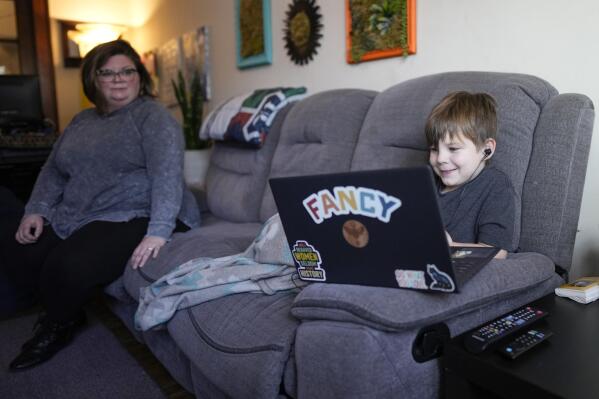 Jessica Blalack, left, watches as her son Phoenix Blalack, 6 , works with a tutor on his laptop in his Indianapolis home, Tuesday, March 7, 2023. (APPhoto/AJ Mast)