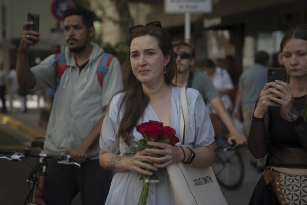 A woman holds flowers outside the Russian Embassy in memory of for jailed Russian opposition leader Alexei Navalny in Buenos Aires, Argentina, Friday, Feb. 16, 2024. (AP Photo/Victor R. Caivano)