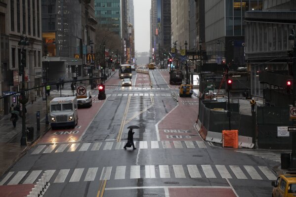 FILE - In this Monday, March 23, 2020 file photo, a man crosses 42nd Street in front of Grand Central Terminal during morning rush hour in New York. Gov. Andrew Cuomo has ordered most New Yorkers to stay home from work to slow the coronavirus pandemic. (AP Photo/Mark Lennihan, File)