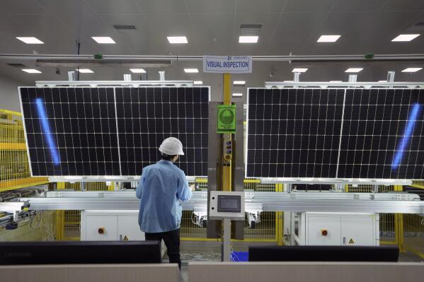 A worker inspects solar panels at Premier Energies Solar on the outskirts of Hyderabad, India, Wednesday, Jan. 25, 2023. Solar developers in India fear that a tax meant to encourage Indian manufacture of solar components will slow down the installation of solar power this year. (AP Photo/Mahesh Kumar A.)