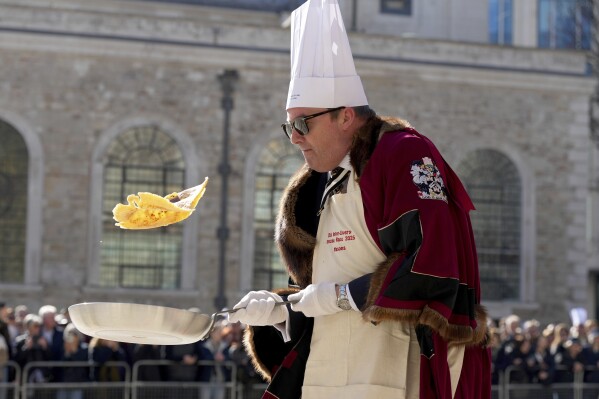 A competitor flips a pancake during a traditional pancake race by livery companies at the Guildhall in London, Tuesday, March 4, 2025.(AP Photo/Frank Augstein)