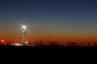 In this Thursday, April 2, 2020 photo, an oil rig lights up the horizon on the outskirts of Midland, Texas after a late sunset. (Odessa American/Eli Hartman)