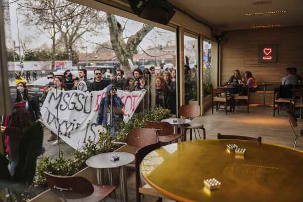 Fine art university students shout slogans as they march past an Expresso Lab coffee bar during a peaceful protest after Istanbul's Mayor Ekrem Imamoglu was arrested and sent to prison, in Istanbul, Turkey, Thursday, March 27, 2025. (AP Photo/Francisco Seco)