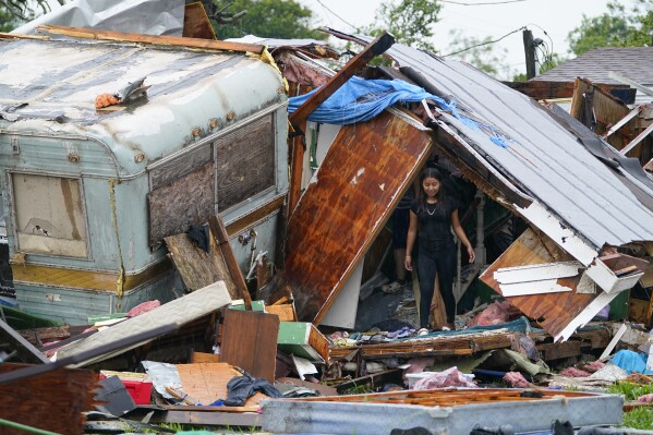 File - A person stands outside of a damaged home after a tornado hit May 13, 2023, in the unincorporated community of Laguna Heights, Texas near South Padre Island. A series of severe thunderstorms in the U.S. resulted in $34 billion in insured losses during the first half of the year, the highest amount ever for insured losses in the period, according to Swiss Re Group. (AP Photo/Julio Cortez, File)