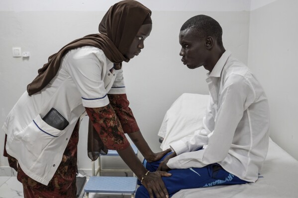 Neurology student Henriette Dieng examines Abdou Diop, a patient with genetic neuropathy at Pedro Rodriguez's clinic in Dakar, Senegal, Friday, Jan. 10, 2025. (AP Photo/Annika Hammerschlag)