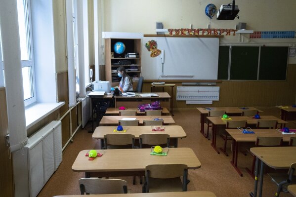 A school teacher gives an online lesson in an empty classroom because one of children is suspected of being infected with the coronavirus in Moscow, Russia, Monday, Sept. 7, 2020. Russian schools, which switched to online classes in late March when the coronavirus pandemic swept the country, have reopened this month. (AP Photo/Pavel Golovkin)