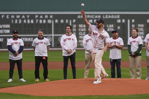 Omer Shem Tov, front, a former Israeli hostage who survived over 500 days in Hamas captivity, delivers a ceremonial first pitch prior to a baseball game between the Boston Red Sox and the New York Mets at Fenway Park, Monday, May 19, 2025, in Boston. (AP Photo/Charles Krupa)