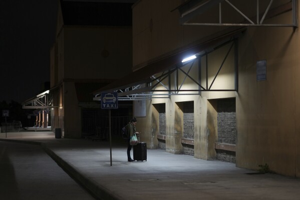 A woman waits for a bus at a station in San Pedro Sula, Honduras, Tuesday, Dec. 3, 2024. (AP Photo/Moises Castillo)