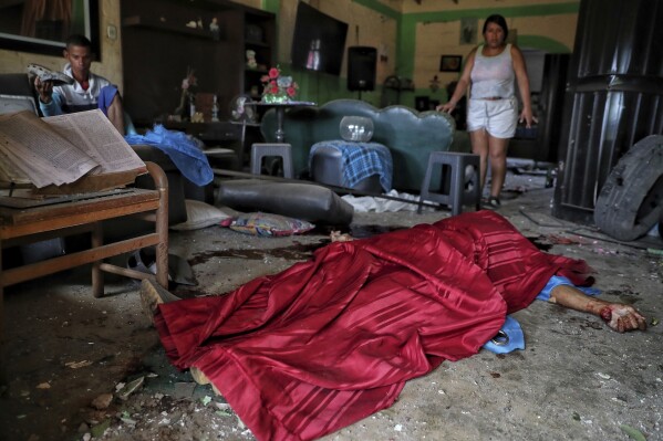 El cuerpo de José Carabali Galeano yace cubierto por una tela roja en su sala después de que una bomba estalló, el 10 de junio de 2025, en Guachinte, Valle del Cauca, Colombia. (AP Foto/Santiago Saldarriaga)