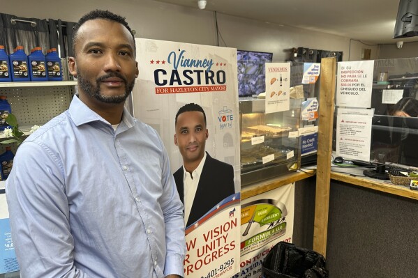 Business owner Vianney Castro poses with a sign from the Hazleton mayoral race he lost last year at his tire store in Hazleton, Pa., on Thursday, May 16, 2024. About two-thirds of district students are Latino, and a federal lawsuit argues that the way representatives are elected to the Hazleton Area School Board is unfairly shutting Latino voters out of power. (AP Photo/Mark Scolforo)