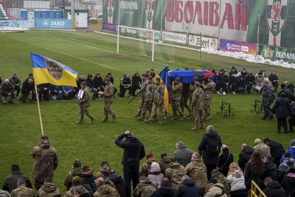 Honor Guards carry portrait and coffin of a Ukrainian officer Pavlo Vedybida aka "Obolonchik" at the Obolon Stadium in Kyiv, Ukraine, Saturday, Nov. 30, 2024. (AP Photo/Evgeniy Maloletka)