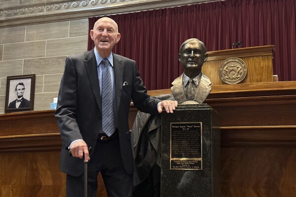 Longtime Missouri basketball coach Norm Stewart poses with his bust after being inducted into the Hall of Famous Missourians at the state Capitol on Wednesday, May 1, 2024, in Jefferson City, Mo. Stewart was immortalized in a bust and joked that he appreciated that his likeness still had hair. (AP Photo/Summer Ballentine)