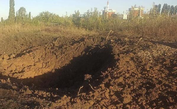 In this photo provided by the South Ukraine nuclear power plant, a crater left by a Russian rocket is seen 300 meter from the South Ukraine nuclear power plant, in the background, close to Yuzhnoukrainsk, Mykolayiv region, Ukraine, Monday, Sept. 19, 2022. (South Ukraine Nuclear Power Plant Press Office via AP)
