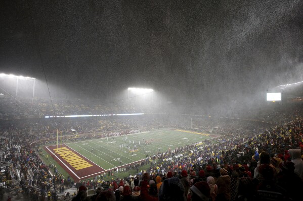 FILE - Snow falls at TCF Stadium during an NCAA college football game between Minnesota and Wisconsin, Saturday, Nov. 30, 2019, in Minneapolis. The Big Ten's longstanding policy to generally not play November night games outdoors after daylight savings ends has been eliminated with the start of the conference's new television contract this season. (AP Photo/Stacy Bengs, File)