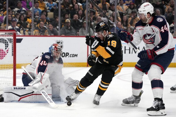 Columbus Blue Jackets goaltender Daniil Tarasov (40) blocks a shot, and Pittsburgh Penguins' Reilly Smith (19) can't get his stick on the rebound with Erik Gudbranson (44) defending during the second period of an NHL hockey game in Pittsburgh, Thursday, March 28, 2024. (AP Photo/Gene J. Puskar)