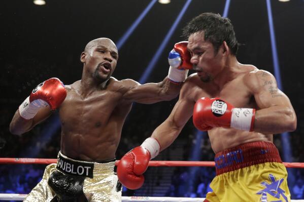 FILE - Floyd Mayweather Jr., left, hits Manny Pacquiao, from the Philippines, during their welterweight title fight on Saturday, May 2, 2015, in Las Vegas. Mayweather Jr. will be inducted into the Boxing Hall of Fame in Canastota, N.Y., on Sunday, June 12, 2022. (AP Photo/Isaac Brekken, File)