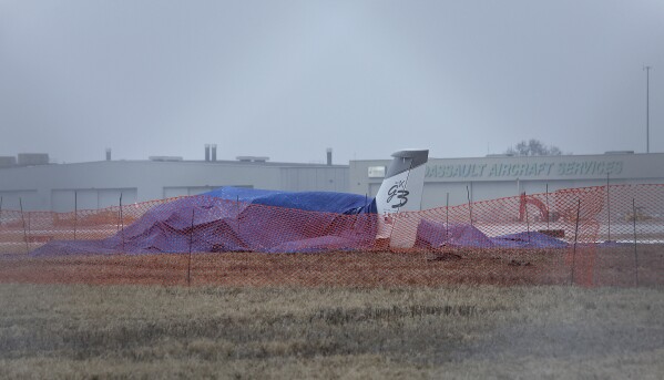 The wreckage of a single-engine Cirrus SR 22 aircraft is covered by a blue tarp near a runway at the Bill and Hillary Clinton National Airport on Monday, Jan. 22, 2024, after it crashed on Sunday in Little Rock, Ark. The pilot of the aircraft was pronounced dead at the scene and was the only individual on board at the time of the incident. (Colin Murphey /Arkansas Democrat-Gazette via AP)