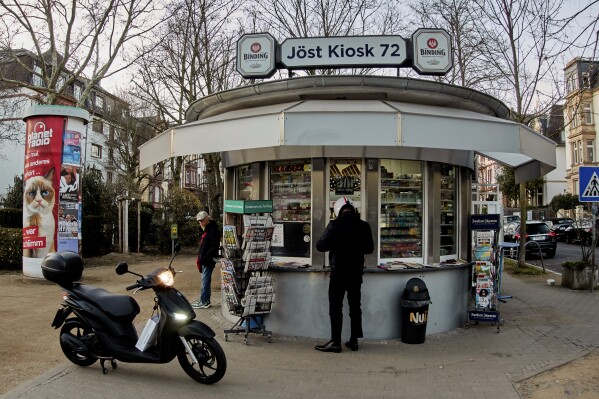 A man buys cigarettes at a former water house, a small shop that sprung up in the 19th century to encourage workers to drink affordable water rather than beer or schnapps, that is now a kiosk in Frankfurt, Germany, on March 17, 2025. (AP Photo/Michael Probst)