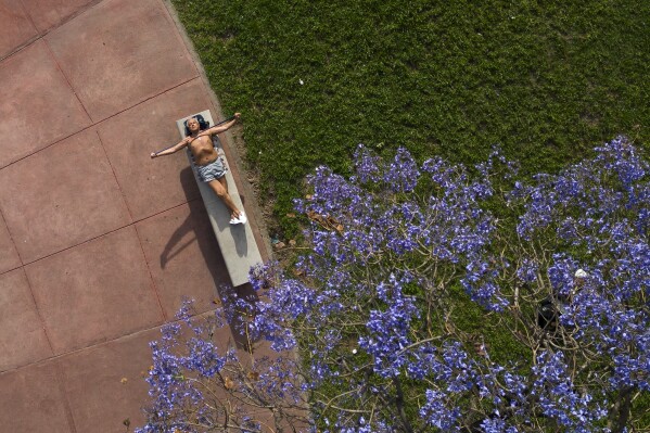 A man stretches an elastic band while sunbathing in downtown Buenos Aires, Argentina, Saturday, Nov. 18, 2023. (AP Photo/Matias Delacroix)