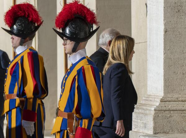 Italian Premier Giorgia Meloni, right, flanked by Monsignor Leonardo Sapienza (partially hidden), walks by Vatican Swiss Guards as she arrives at The Vatican, Tuesday, Jan. 10, 2023 for an audience with Pope Francis. (AP Photo/Domenico Stinellis)