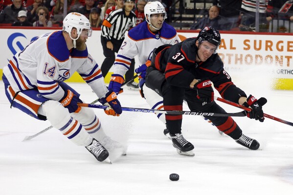 Carolina Hurricanes' Andrei Svechnikov (37) tries to control the puck between Edmonton Oilers' Evan Bouchard (2) and Mattias Ekholm (14) during the second period of an NHL hockey game in Raleigh, N.C., Wednesday, Nov. 22, 2023. (AP Photo/Karl B DeBlaker)