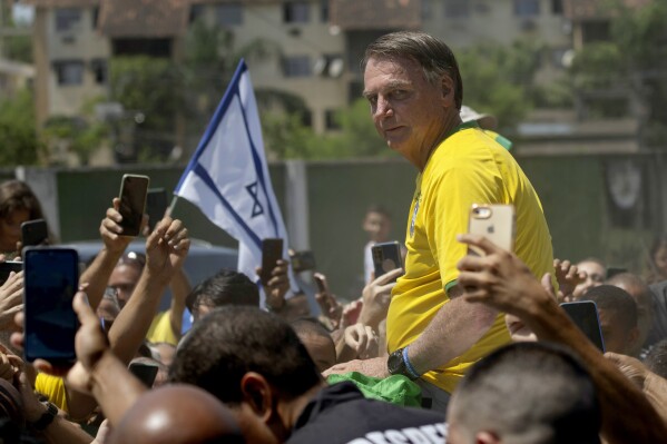 FILE - Brazil's former President Jair Bolsonaro is surrounded by supporters after attending a campaign event launching the pre-candidacy of a mayoral candidate, in Rio de Janeiro, Brazil, March 16, 2024. Brazil’s top justice minister Alexandre de Moraes denied Bolsonaro’s request that his passport be returned to him so that he can travel to Israel, according to a Supreme Court document released on Friday, March 29, 2024. (AP Photo/Silvia Izquierdo, File)