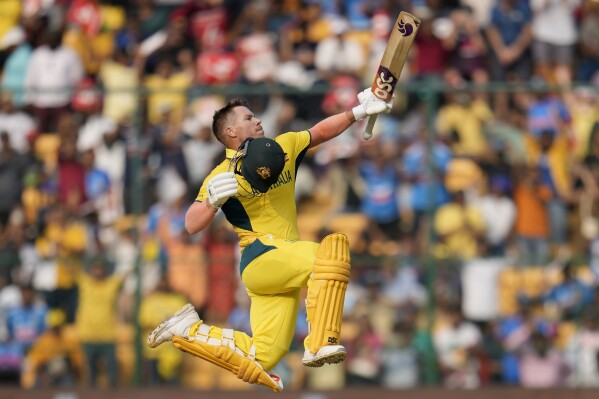 Australia's David Warner leaps to celebrate scoring a century during the ICC Men's Cricket World Cup match between Australia and Pakistan in Bengaluru, India, Friday, Oct. 20, 2023. (AP Photo/Aijaz Rahi)