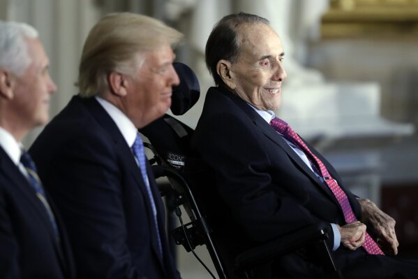 FILE - In this Jan. 17, 2018 file photo, President Donald Trump, center and Vice President Mike Pence watch during a Congressional Gold Medal ceremony honoring former Senator Bob Dole on Capitol Hill in Washington. Political icon and 1996 Republican presidential nominee Bob Dole says he has been diagnosed with stage 4 lung cancer. The 97-year-old former U.S. Senate majority leader said Thursday in a short statement that he would begin treatment for the disease Monday. (AP Photo/Evan Vucci)