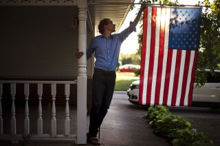 FILE - In this Aug. 18, 2020, file photo, Outagamie County Executive Tom Nelson adjusts the American flag hanging off his front porch in Appleton, Wis. Nelson officially launched his bid to unseat ...