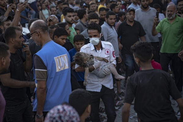 A child is carried from the rubble of a building after an airstrike in Khan Younis, Gaza Strip, Saturday, Oct. 21, 2023. (AP Photo/Fatima Shbair)