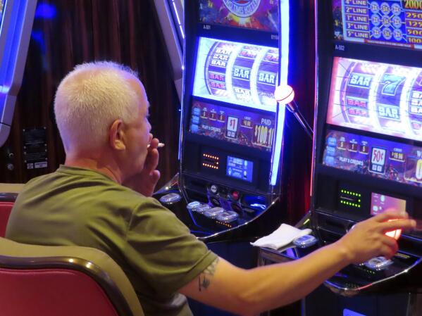 A gambler smokes while playing a slot machine at the Hard Rock casino in Atlantic City N.J. on Aug. 8, 2022. On Monday Feb. 13, 2023, lawmakers will hold their first hearing on a bill that would ban smoking in Atlantic City's nine casinos. (AP Photo/Wayne Parry)
