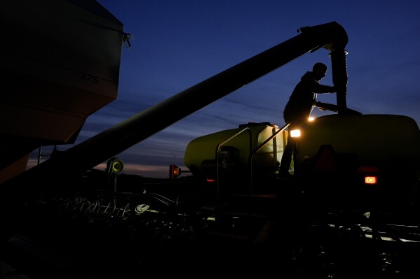 Mark Woodruff loads more soybean seeds into a planter April 22, 2024, in Sabina, Ohio. (AP Photo/Joshua A. Bickel, File)