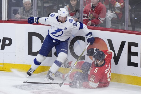 Tampa Bay Lightning center Steven Stamkos (91) and Florida Panthers defenseman Aaron Ekblad (5) battle for the puck during the first period of Game 5 of the first-round of an NHL Stanley Cup Playoff series, Monday, April 29, 2024, in Sunrise, Fla. (AP Photo/Wilfredo Lee)