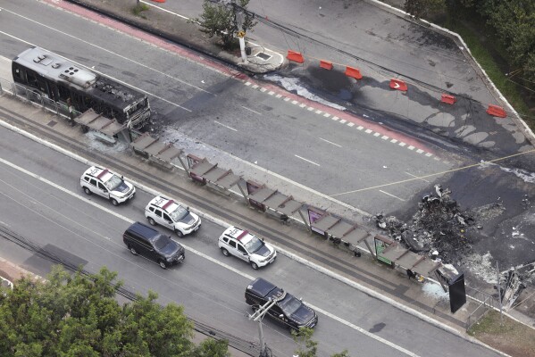 The crash site of a small plane, right, that burned a bus, left, covers an avenue in Sao Paulo, Friday, Feb. 7, 2025. (AP Photo/Ettore Chiereguini)