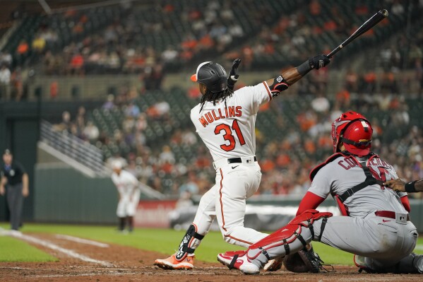 Baltimore Orioles' Cedric Mullins (31) follows through on a swing as he and St. Louis Cardinals catcher Willson Contreras watch the ball on a grand slam off relief pitcher Andre Pallante in the fifth inning of a baseball game, Monday, Sept. 11, 2023 in Baltimore. Orioles' Gunnar Henderson, Ryan O'Hearn and Ryan Mountcastle scored on the grand slam. (AP Photo/Julio Cortez)