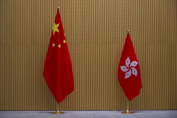 FILE- In this Monday, March 2021 ,file photo, a China national flag, left, and a Hong Kong flag are displayed at central government office in Hong Kong. China's top legislature approved amendments to Hong Kong's constitution on Tuesday, March 30, that will give Beijing more control over the make-up of the city's legislature. (AP Photo/Vincent Yu, File)