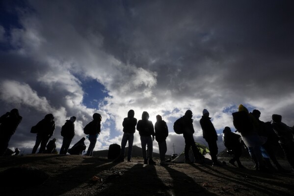 Asylum-seeking migrants wait to be processed in a makeshift, mountainous campsite after crossing the border with Mexico, Friday, Feb. 2, 2024, near Jacumba Hot Springs, Calif. (AP Photo/Gregory Bull)