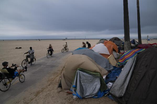 FILE - People ride their bikes past a homeless encampment set up along the boardwalk in the Venice neighborhood of Los Angeles on June 29, 2021. Democratic Mayor Karen Bass, who was elected in November 2023 after promising to take on the city’s out-of-control homeless crisis, announced Monday, April 17, she would recommend spending what she called a record $1.3 billion next year to get unhoused people into shelter and treatment programs. (AP Photo/Jae C. Hong, File)