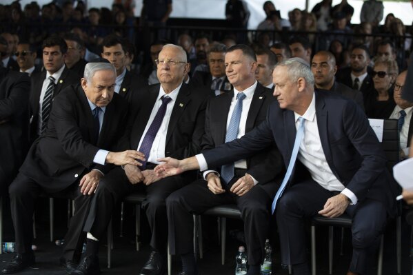 Blue and White Party leader Benny Gantz, right, reaches out to shake hands with Israeli Prime Minister Benjamin Netanyahu at an official memorial for former Israeli Prime Minister Yitzhak Rabin and his wife Leah, commemorating 24 years since the assassination of Rabin, at Mt. Herzl in Jerusalem, Sunday, Nov. 10, 2019. (Heidi Levine/Pool via AP)