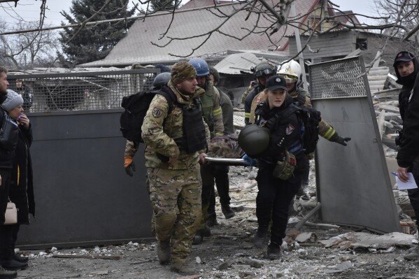 FILE - Ukrainian emergency workers and servicemen carry the body of a resident killed in Russia's massive air attack in Zaporizhzhia, Ukraine, Friday, Dec. 29, 2023. TThe United Nations said in a new report Tuesday, Jan. 16, 2024, Russia’s intense missile and drone attacks across Ukraine in recent weeks sharply increased civilian casualties in December, with over 100 killed and nearly 500 injured. (AP Photo/Andriy Andriyenko, File)