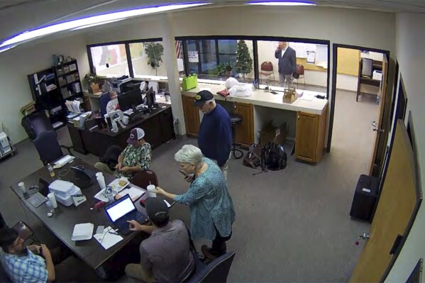 FILE - In this Jan. 7, 2021, image taken from Coffee County, Ga., security video, Cathy Latham, center, is seen in the local elections office in Douglas, Ga., while a computer forensics team was there to make copies of voting equipment. Latham was the county Republican Party chair at the time. (Coffee County, Georgia via AP, File)