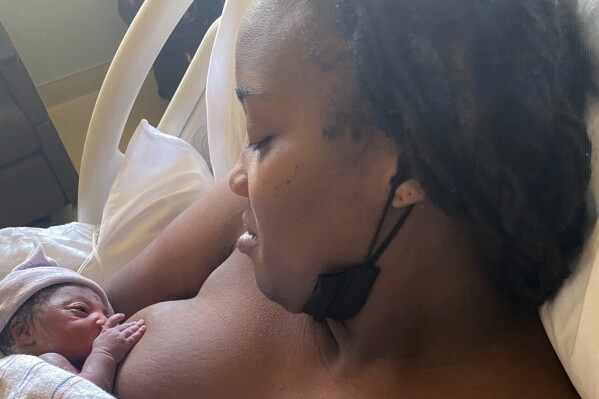 This 2021 photo provided by Ci Ci Covin shows her nursing her newborn, Zuri, in Philadelphia. When Covin, diagnosed with HIV over a decade earlier, became pregnant with her now 2-year-old daughter, her health care team helped her successfully breastfeed for seven months. Covin took her prescriptions as directed and also gave the baby drugs to prevent infection. (Courtesy Ci Ci Covin via AP)