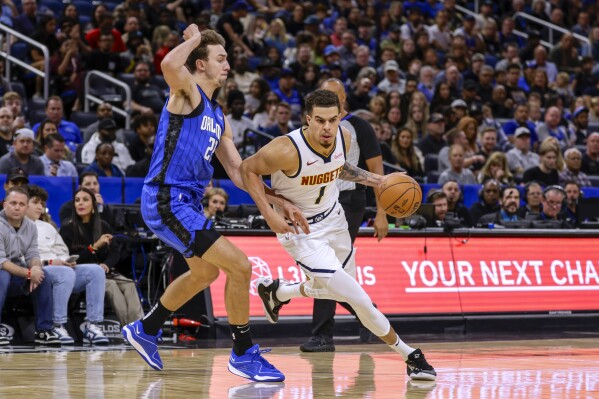 Denver Nuggets forward Michael Porter Jr. (1) is defended by Orlando Magic forward Franz Wagner (22) during the first half of an NBA basketball game Wednesday, Nov. 22, 2023, in Orlando, Fla. (AP Photo/Kevin Kolczynski)