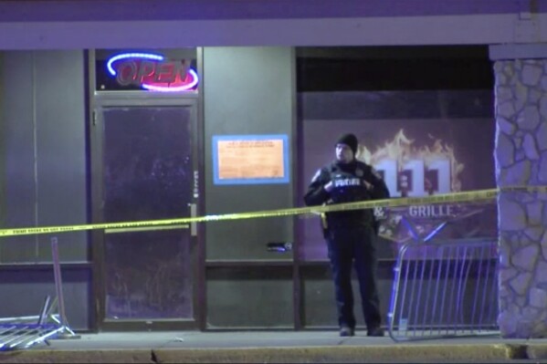 A police officer stands outside a bar after a shooting early Sunday, March 24, 2024 in Indianapolis. Two Indianapolis Metropolitan Police Department officers in full uniform were working in off-duty employment at the bar when there was a disturbance in the parking lot around 1:30 a.m., Chief Christopher Bailey said during a news conference at the scene. (WRTV via AP)