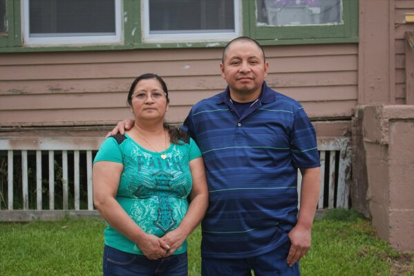 In this photo provided by Cristobal Francisquez, his parents Paulina and Marcos Francisco pose for a photo in front of their house in Sioux City, Iowa, Monday, May 25, 2020. They bought the home after years of working in a meatpacking plant and other food processing jobs. (Cristobal Francisquez via AP)