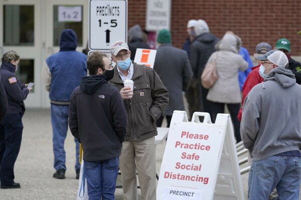 Voters wait in line outside a polling station at Marshfield High School, Tuesday, Nov. 3, 2020, in Marshfield, Mass. (AP Photo/Steven Senne)