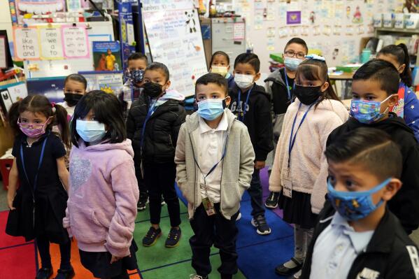 FILE - Kindergarteners wear masks while listening to their teacher amid the COVID-19 pandemic at Washington Elementary School on Jan. 12, 2022, in Lynwood, Calif. The governors of California, Oregon and Washington have announced that schoolchildren will no longer required to wear masks starting March 12, 2022. The governors of the three states announced the measure in a joint statement as part of new indoor mask policies that come as coronavirus case and hospitalization rates decline across the West Coast. (AP Photo/Marcio Jose Sanchez, File)
