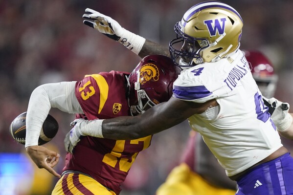 Washington defensive end Zion Tupuola-Fetui, right, forces a fumble by Southern California quarterback Caleb Williams during the first half of an NCAA college football game Saturday, Nov. 4, 2023, in Los Angeles. (AP Photo/Ryan Sun)